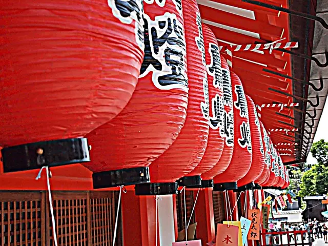 In this image I see the Chinese lanterns which are of red in color and I see colorful papers on...