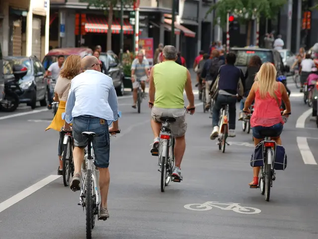 There are some people cycling on the roads. On the right corner and left corner we can see cars. In...